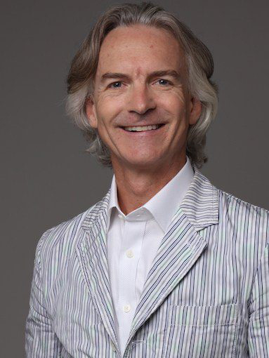 Smiling portrait of Minter Dial in collared shirt and blazer
