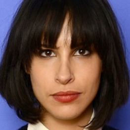 Desiree Akhavan in front of a Blue Background