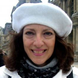 Scholar Alma Gotlieb in a white beret standing in front of buildings