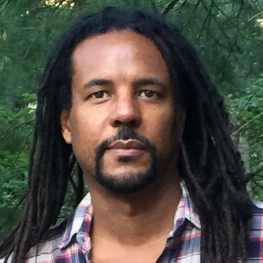 Headshot of author Colson Whitehead standing in front of trees