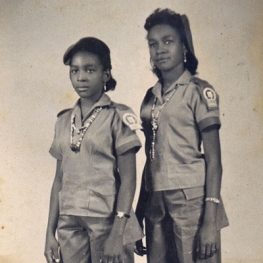 Two Cuban women in military outfits posing side by side in a vintage photograph
