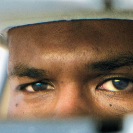 Close up of a person's face in a rear view mirror from Film poster of The Oath (dir. Laura Poitras, 2010, 96 min.)