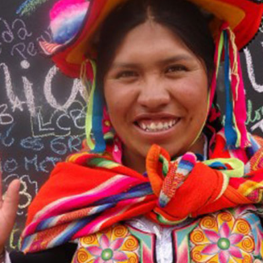 Film still from Sonia's Dream. Sonia Mamani, an Aymara chef standing in front of a chalkboard filled with phrases in Espanol.