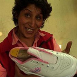 Film still from Vivir La Chicha. Woman holding a sneaker.
