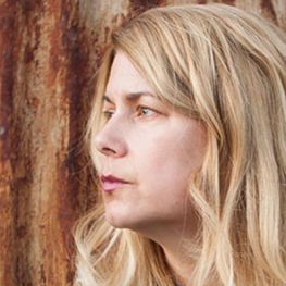 portrait of writer Lydia Millet standing in front of a tree