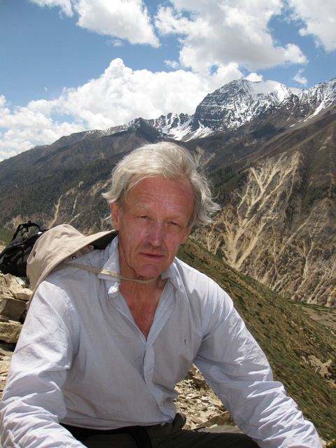 Older fit white male on top of a mountain with a sun hat on